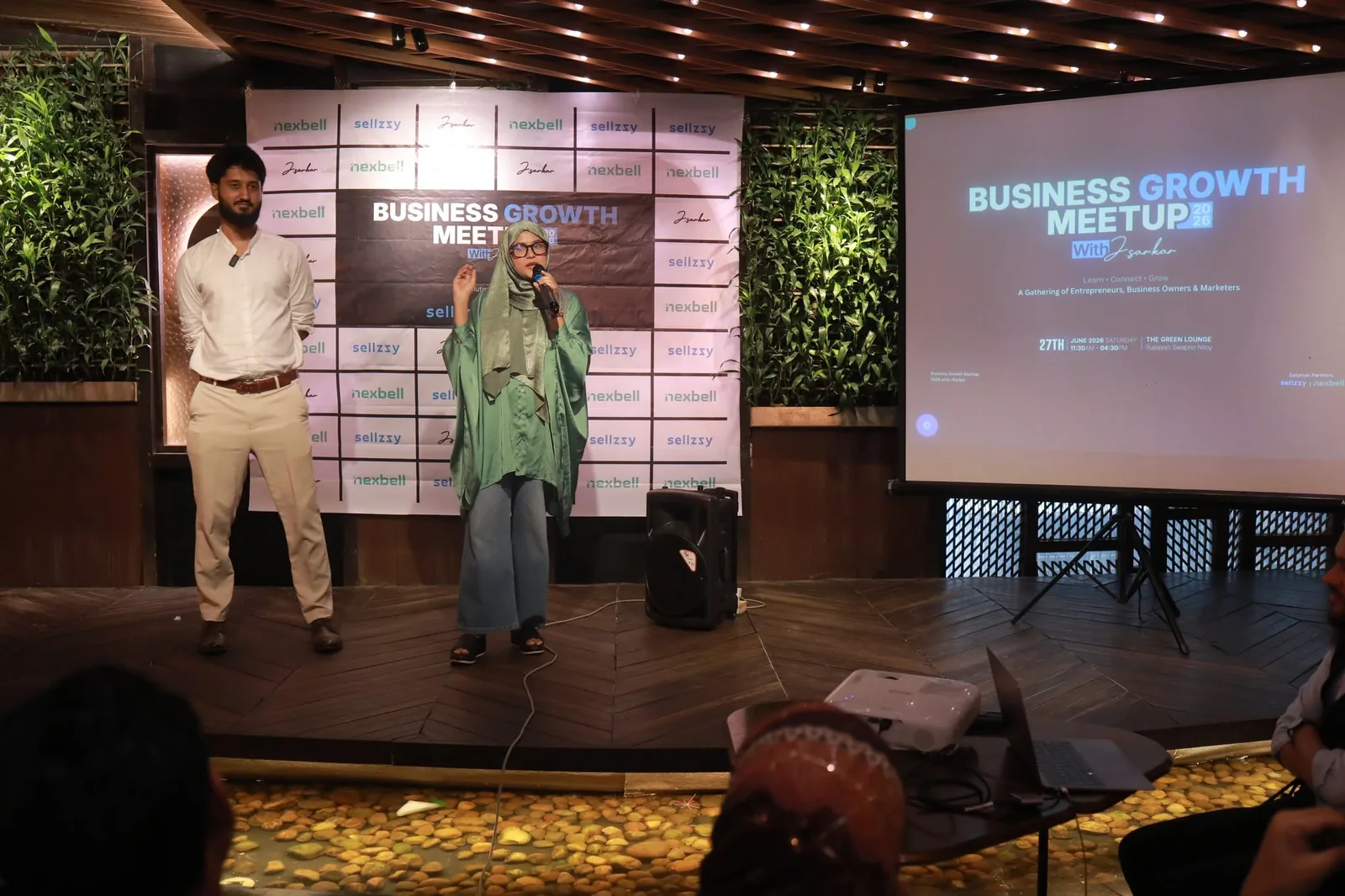 মঞ্চে Business Growth Meetup 2026 উপস্থাপনা, স্ক্রিনে ইভেন্টের তারিখ ও সলিউশন পার্টনার Sellzzy